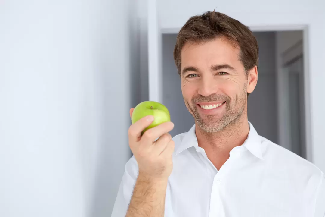 Ein Mann isst einen Apfel, um seine Potenz zu steigern